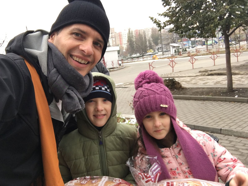 about-end-world-hunger-2045 one man and two children dressed in hats and scarfs smiling on a foggy day
